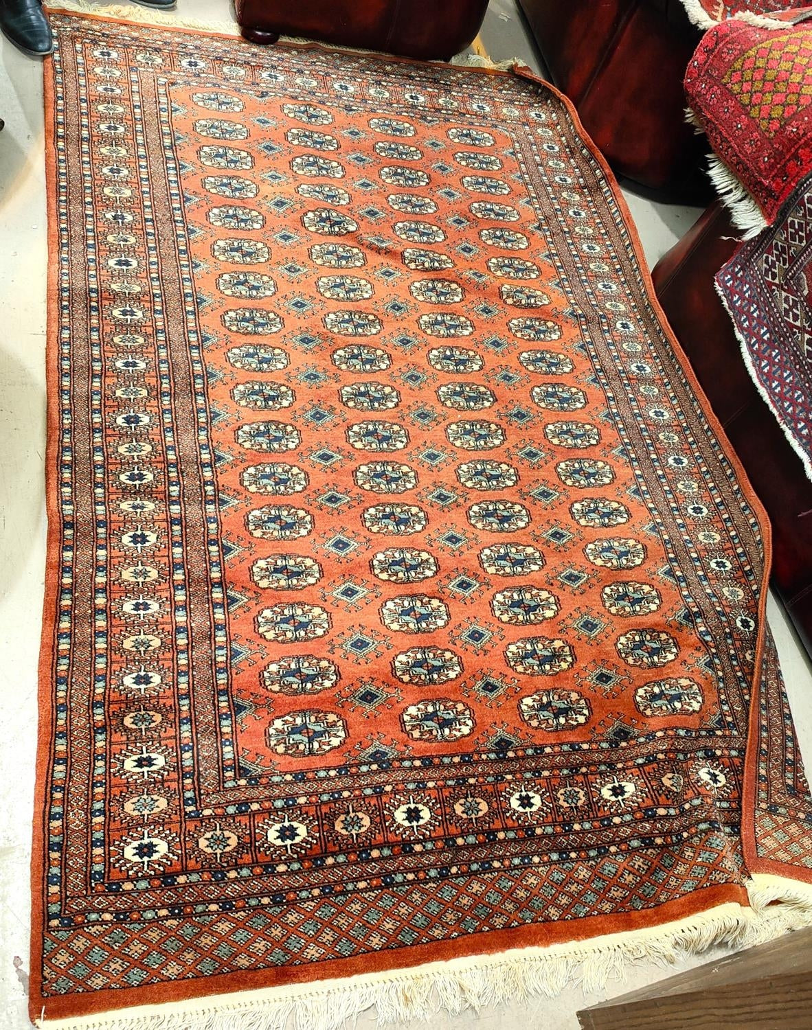 A 20th century hand knotted rust ground Bokhara carpet with four lines of guls to centre