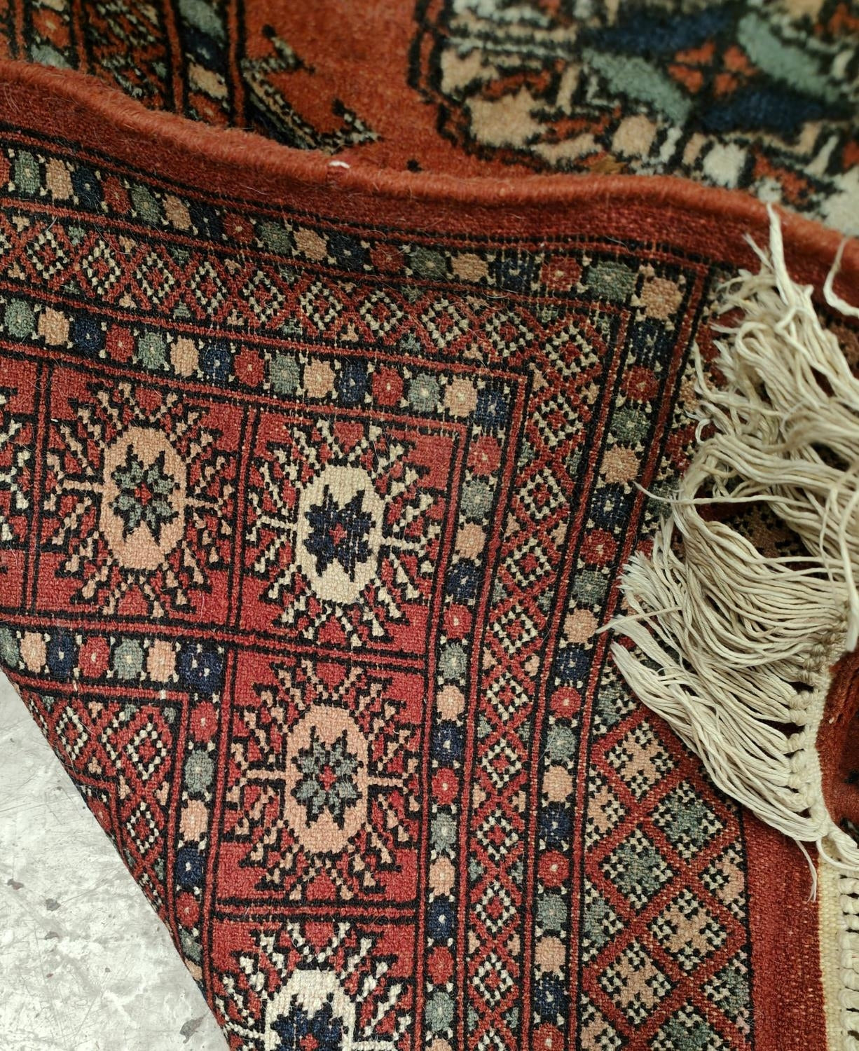 A 20th century hand knotted rust ground Bokhara carpet with four lines of guls to centre