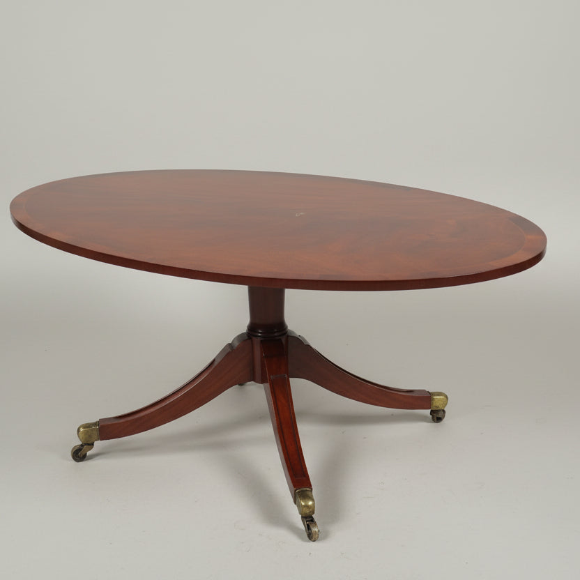 An inlaid oval coffee table on four splay feet with brass casters