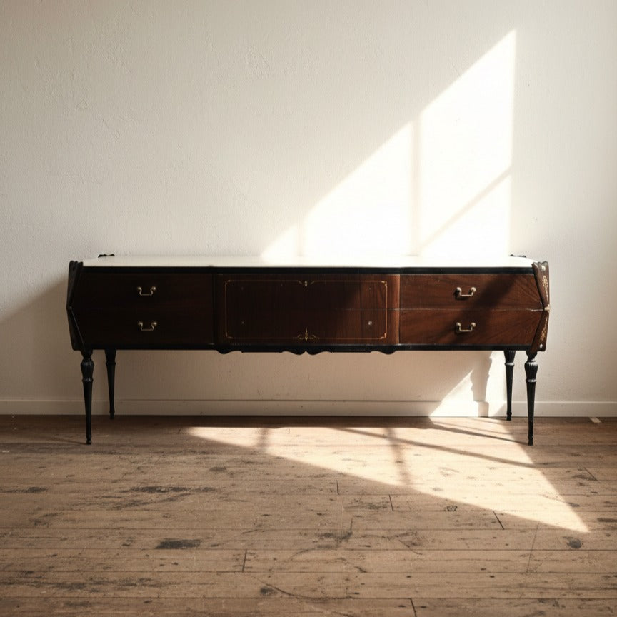 Wooden dresser with a dark finish in a room with sunlight streaming through a window.