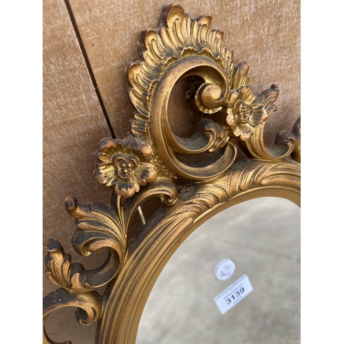 AN ORNATE OVAL GILT FRAMED MIRROR