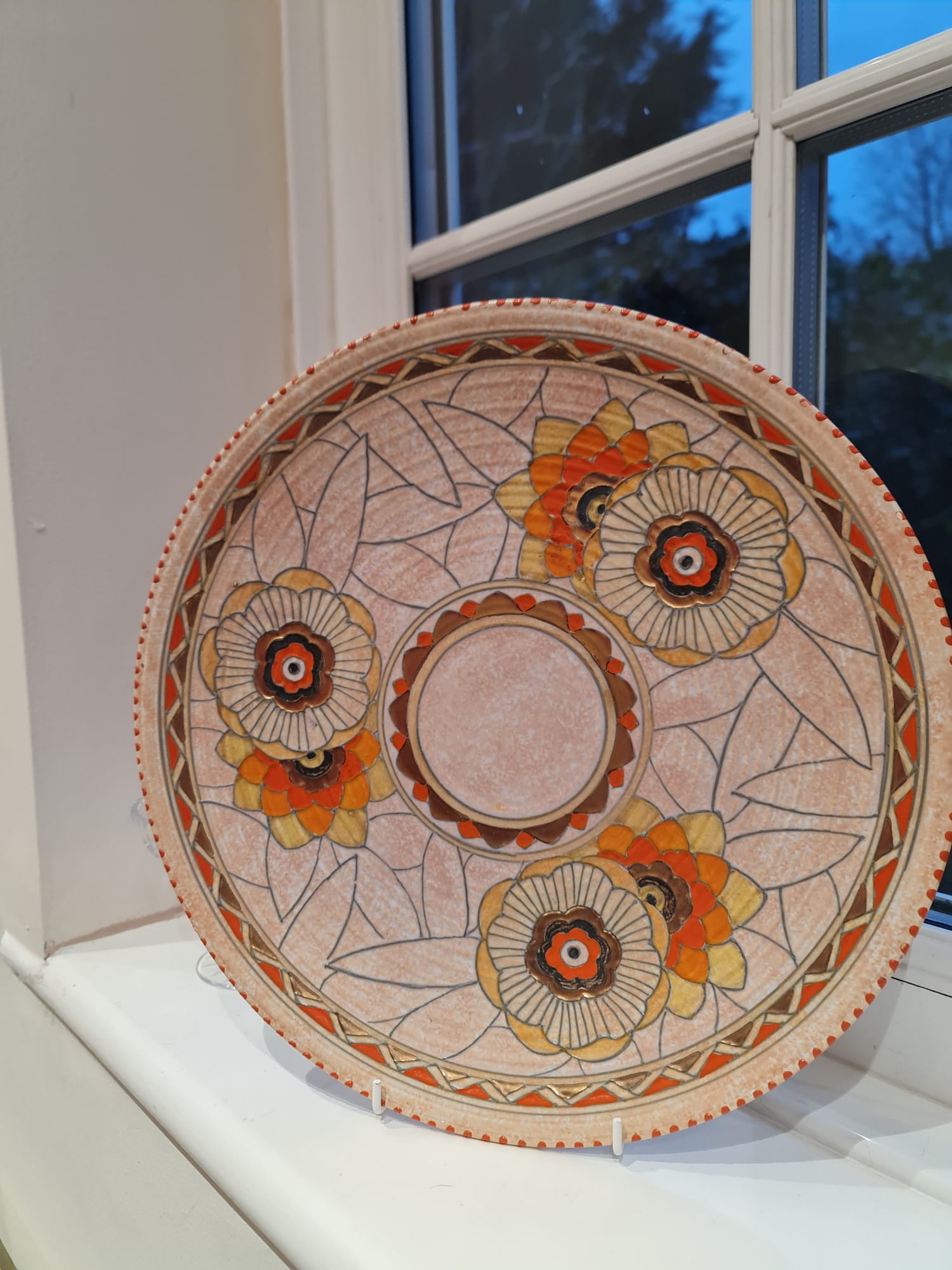This collector plate, designed by Charlotte Rhead, features an intricate pattern of leaves and showcases the Art Deco style.