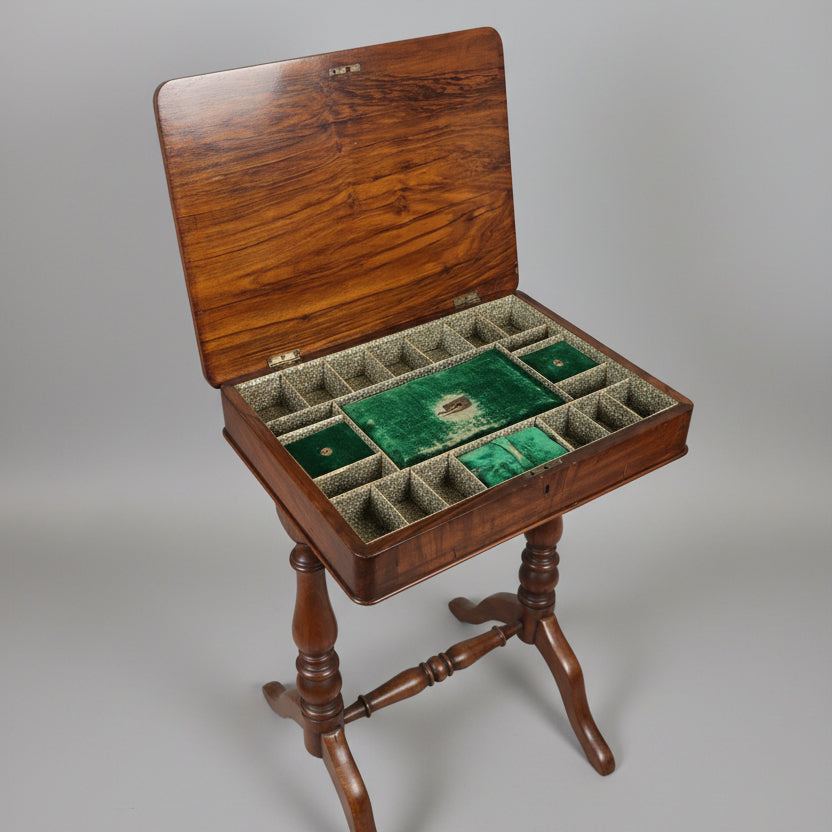 An open wooden game board or mahjong-style storage table with a green felt playing field and multiple divided compartments, shown in a furniture showroom.