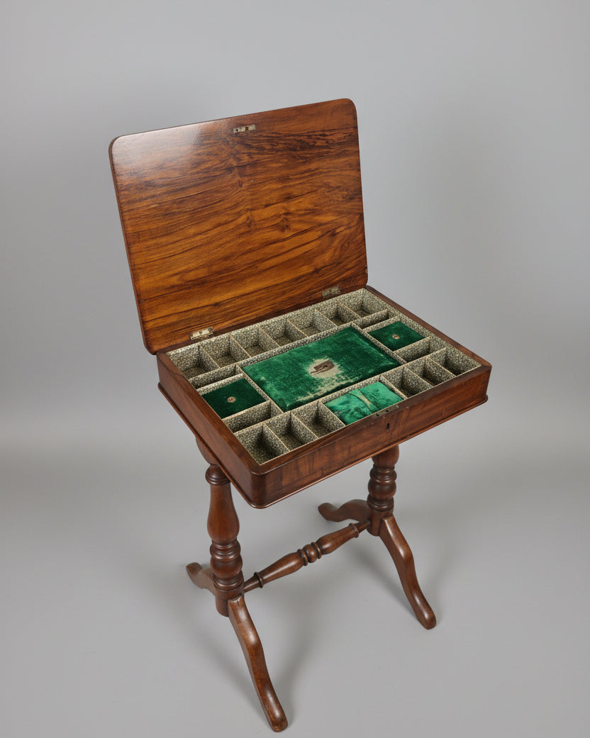 An open wooden game board or mahjong-style storage table with a green felt playing field and multiple divided compartments, shown in a furniture showroom.