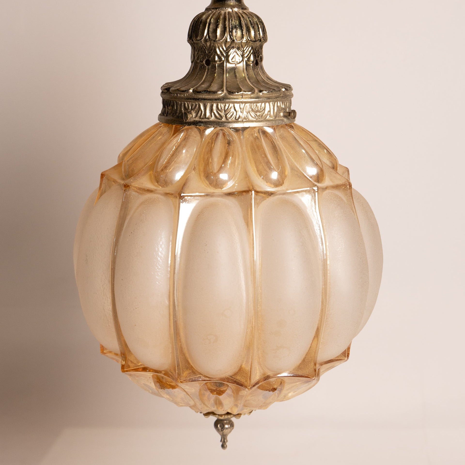 Vintage-style pendant light with decorative glass shade on a plain background
