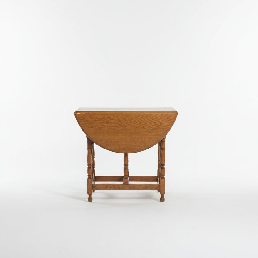 Wooden drop-leaf table on a textured floor with a plain wall background