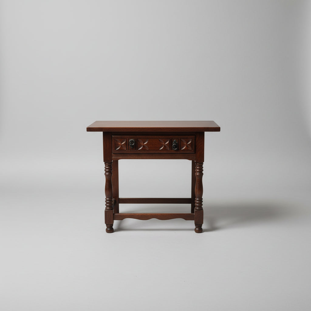 A 19th century oak wood table with a carved frieze drawer on turned supports, placed on a woven mat.