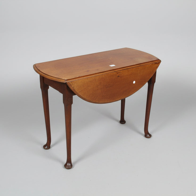19th century oval mahogany drop-leaf table with tapered legs and pad feet, positioned on a concrete surface with a visible red paint marking.