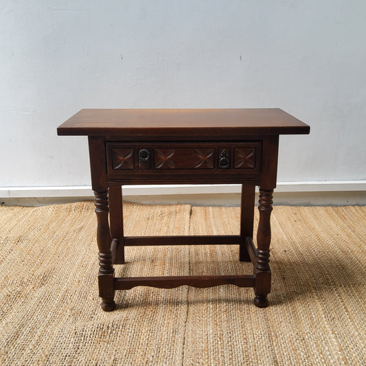 An oak side table, with a carved frieze drawer on turned supports.