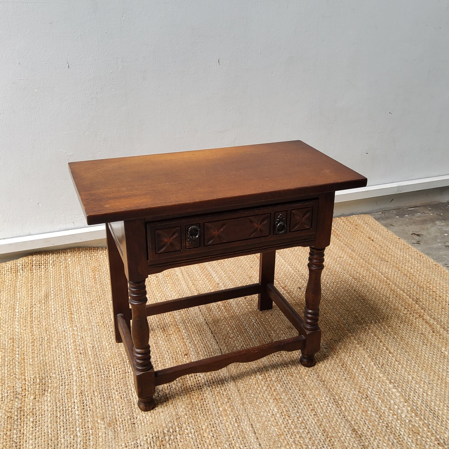 An oak side table, with a carved frieze drawer on turned supports.