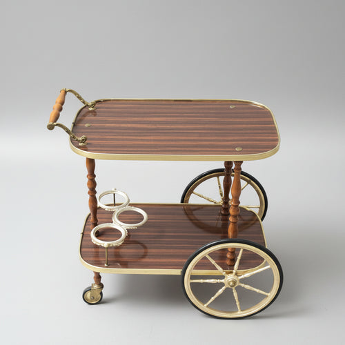 Wooden tea cart with brass accents on a red patterned rug, branded 'The British Antiques Company'.
