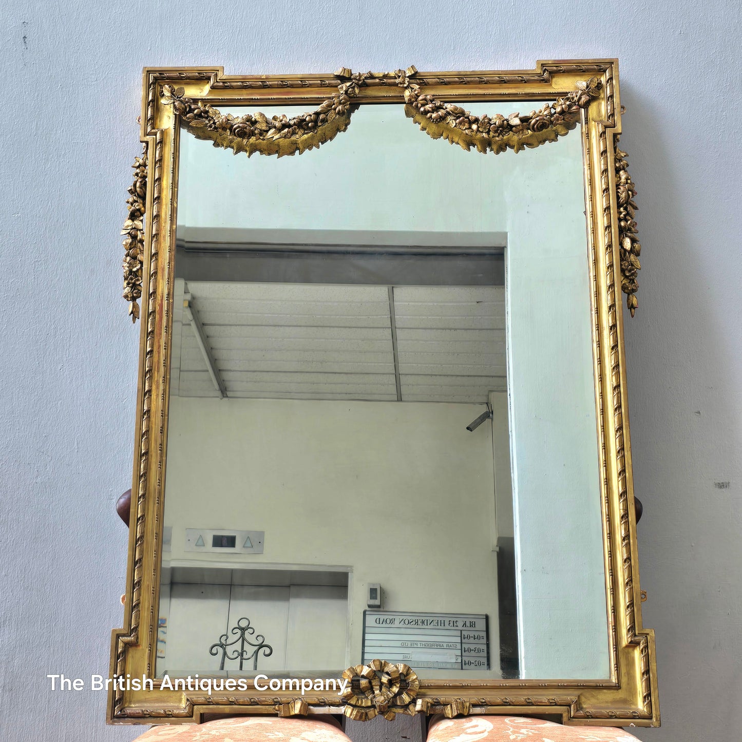 A 19TH CENTURY GILT WALL MIRROR WITH BEVEL EDGE AND DECORATED WITH SWAGS, 47" X 38"