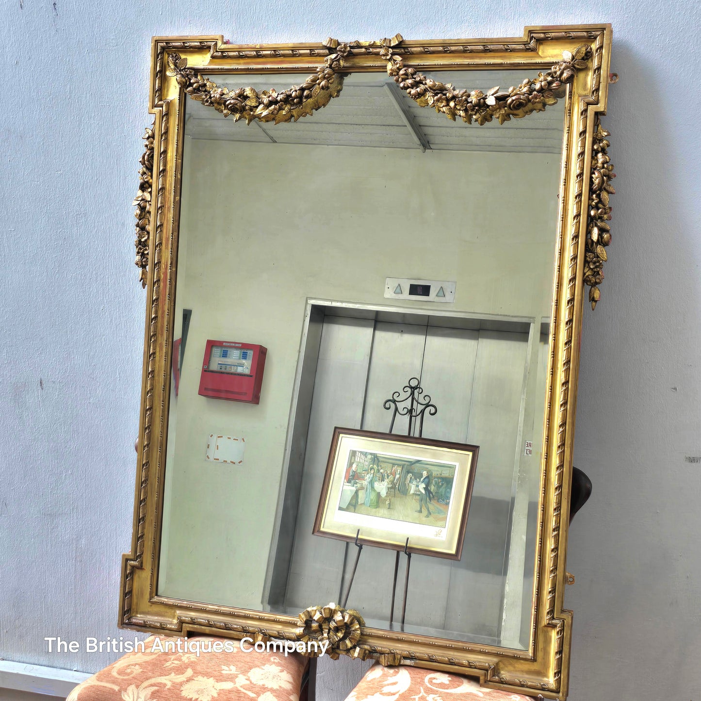 A 19TH CENTURY GILT WALL MIRROR WITH BEVEL EDGE AND DECORATED WITH SWAGS, 47" X 38"