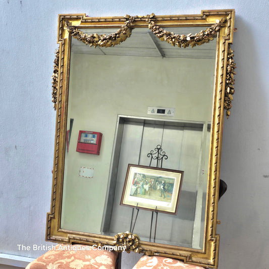 A 19TH CENTURY GILT WALL MIRROR WITH BEVEL EDGE AND DECORATED WITH SWAGS, 47" X 38"
