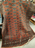 A 20th century hand knotted rust ground Bokhara carpet with four lines of guls to centre