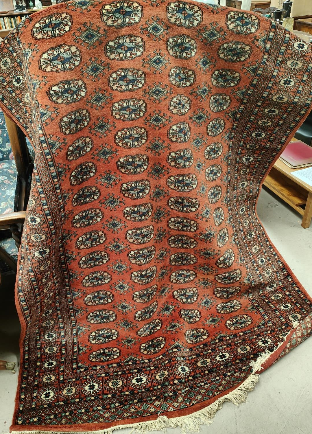 A 20th century hand knotted rust ground Bokhara carpet with four lines of guls to centre