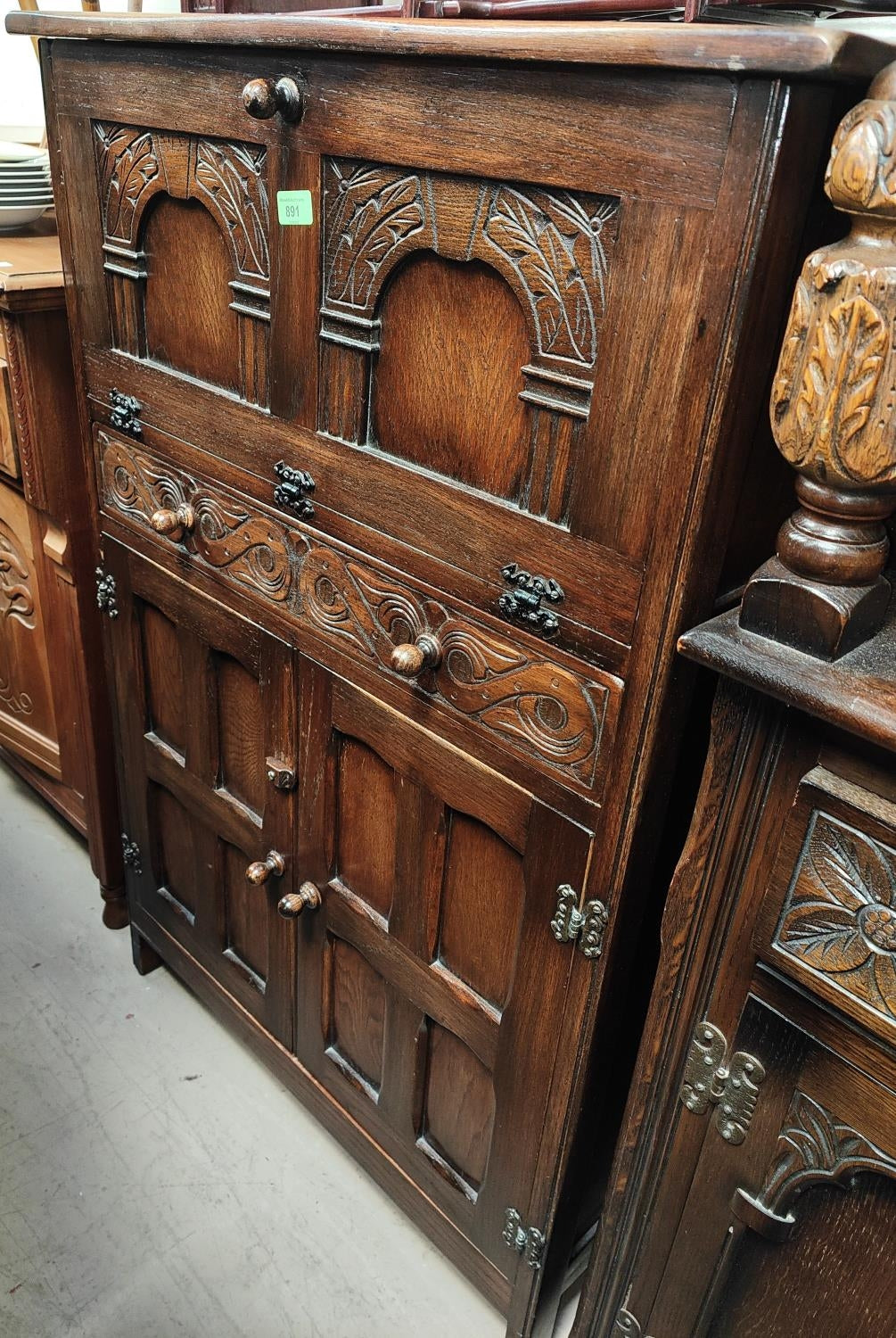A Jacobean style carved oak Cocktail Drink cabinet with fall front over drawer and double cupboard