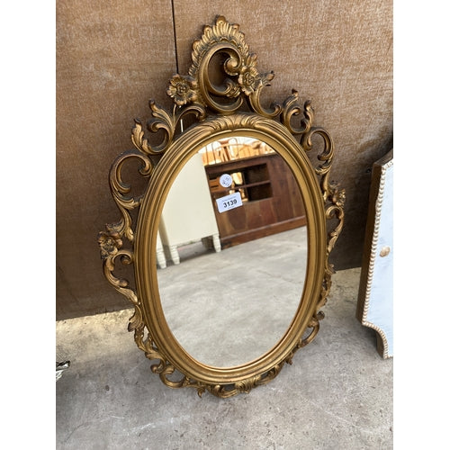 AN ORNATE OVAL GILT FRAMED MIRROR