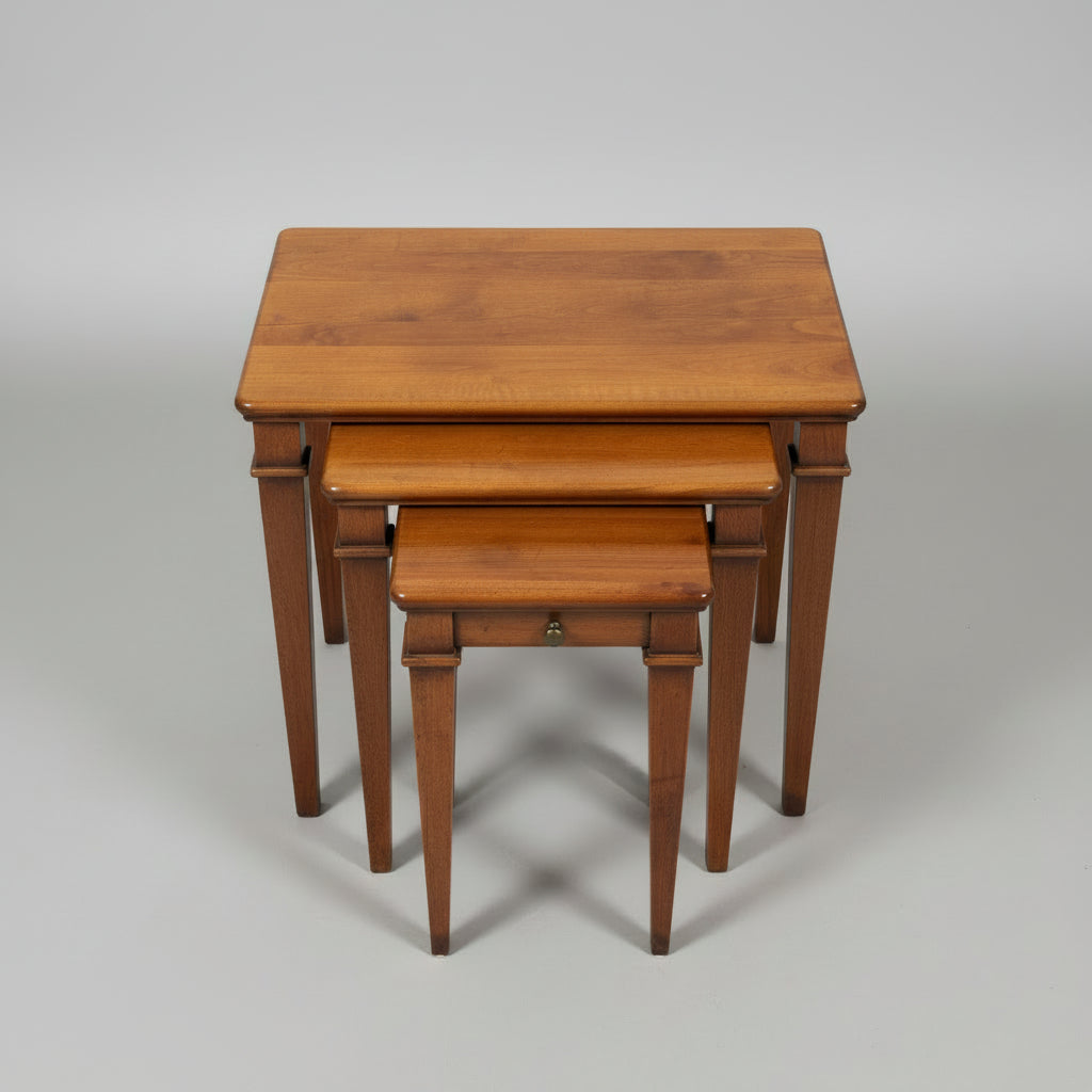 A set of three nested wooden nesting tables with a warm medium-brown finish, photographed on a distressed concrete floor.
