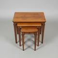A set of three nested wooden nesting tables with a warm medium-brown finish, photographed on a distressed concrete floor.