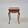 Wooden side table on a red patterned rug with decorative elements.