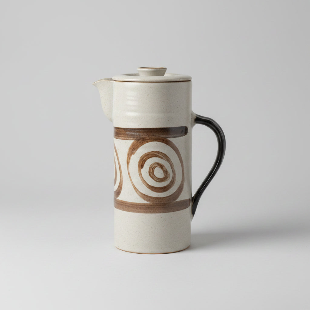 Coffee cup with a brown spiral design on a white surface near a window.