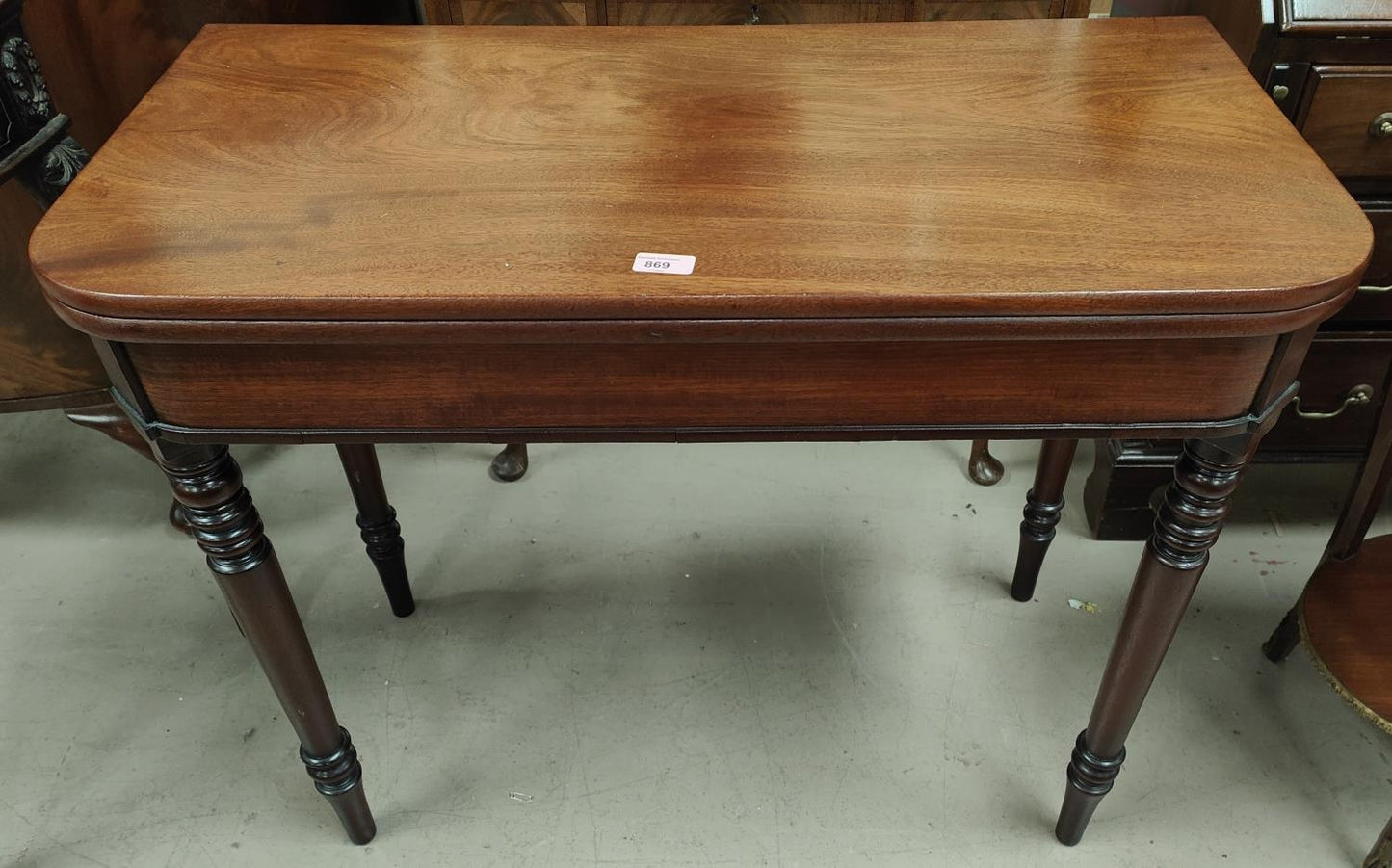 A mahogany tea table with turned legs, rounded rectangular folding top.
