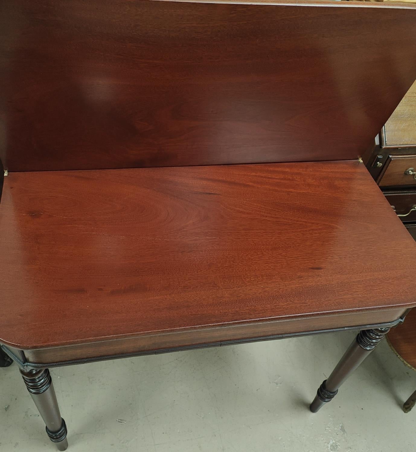 A mahogany tea table with turned legs, rounded rectangular folding top.