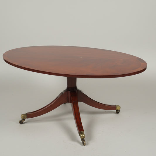 An inlaid oval coffee table on four splay feet with brass casters