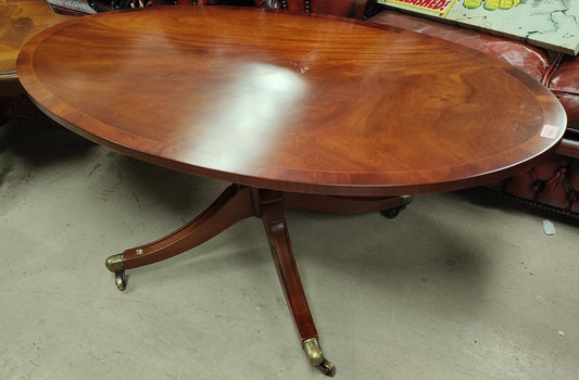An inlaid oval reproduction coffee table on four splay feet with brass casters