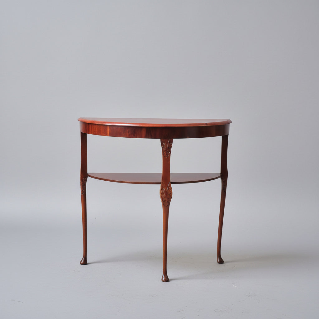 Wooden side table with decorative items in a room with a chair and small table.