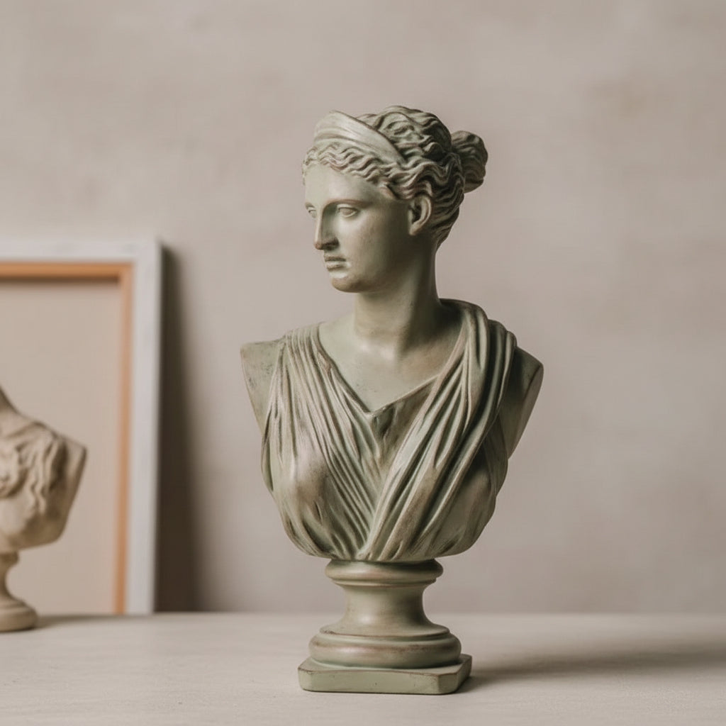 A classical-style stone bust sculpture of a draped female figure, displayed against a dark textured wall with vintage sheet music and draped fabric in the background.