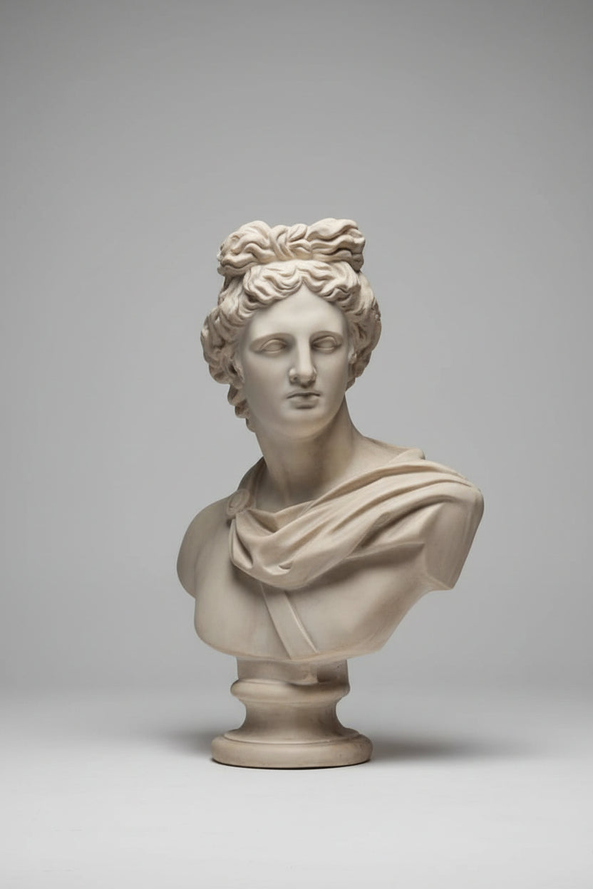 A classical-style stone bust sculpture of a woman with curly hair, displayed on a pedestal against an elegant white paneled wall.