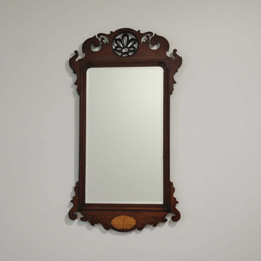 Decorative wall mirror with wooden frame on a plain wall