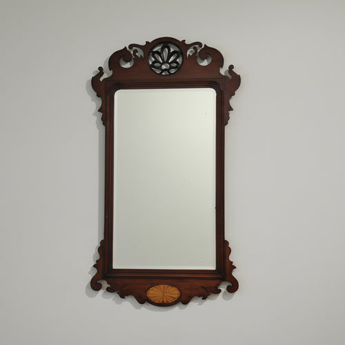 Decorative wall mirror with wooden frame on a plain wall