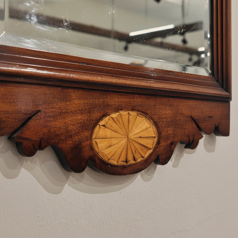 Wooden mirror frame with decorative element on a white wall