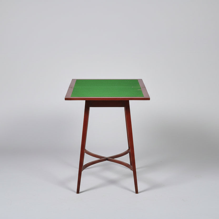 Small wooden table with a green felt surface on a red patterned rug.