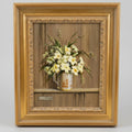 Framed artwork of a still life with flowers in a vase on a wooden surface.