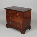 An early 19th century small mahogany chest of drawers with oak lining and original handles, displayed on a shaped apron.