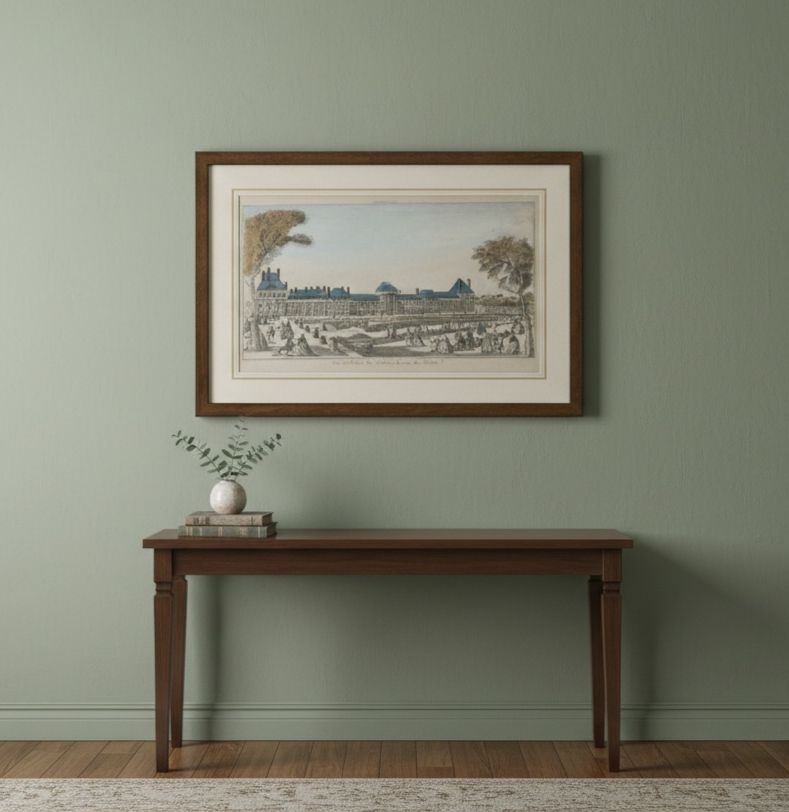 Framed artwork on a wall above a wooden table with a plant and books.