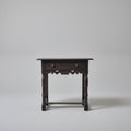 Wooden side table with decorative items on a red patterned rug against a white wall.