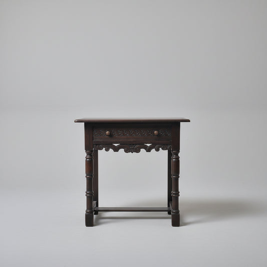 Wooden side table with decorative items on a red patterned rug against a white wall.