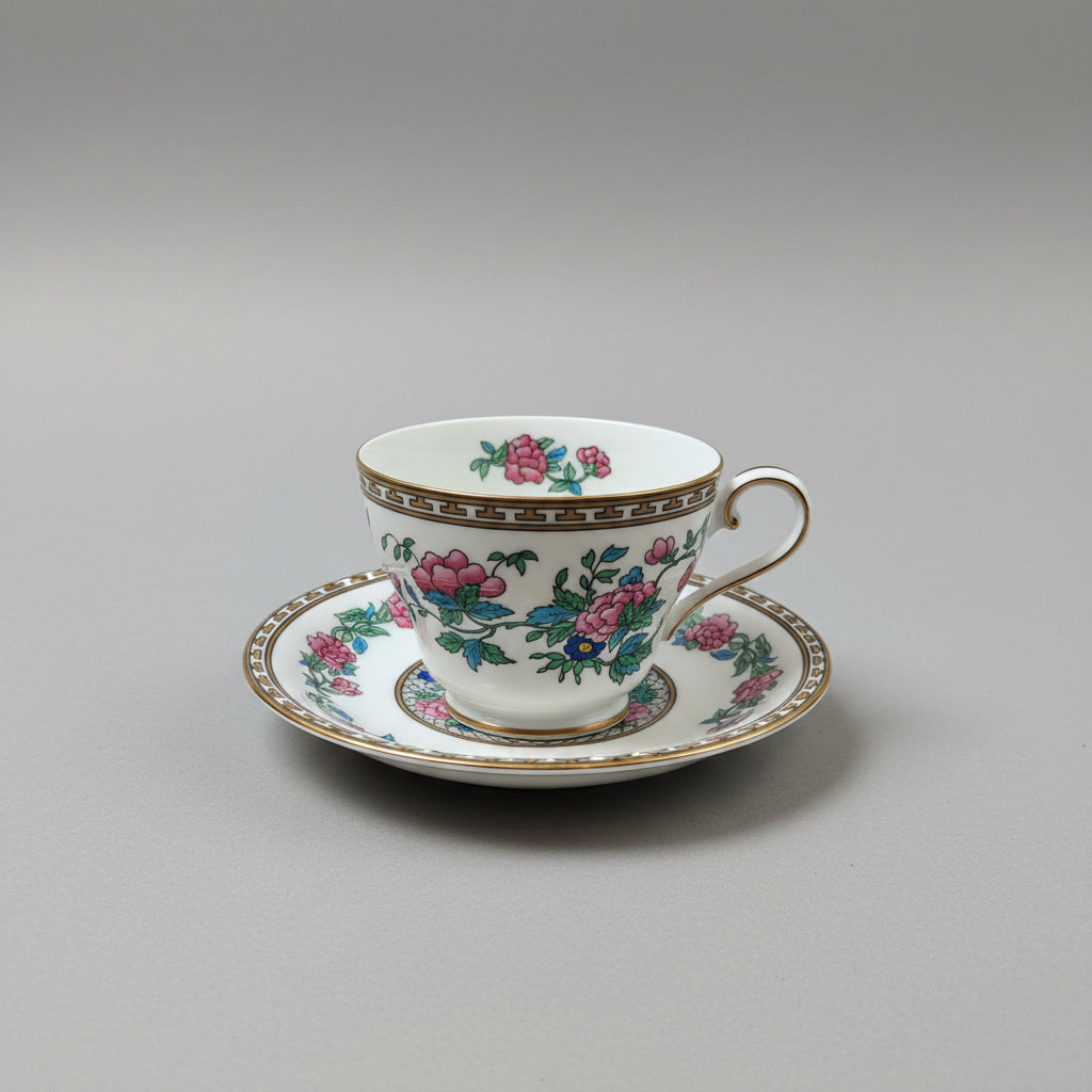 Decorative teacup and saucer with floral patterns on a wooden surface