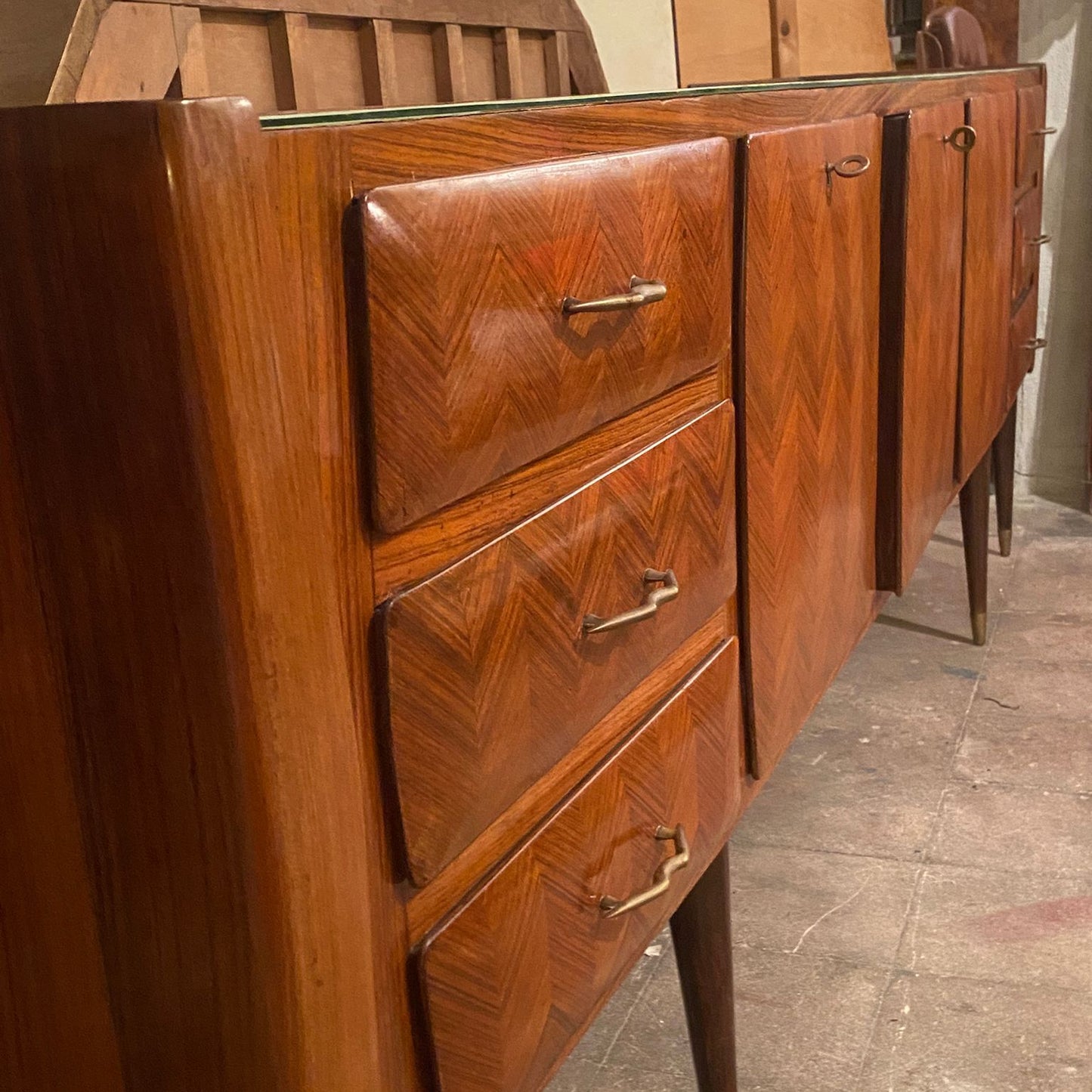 Wooden dresser with chevron pattern and metal handles on a concrete floor.