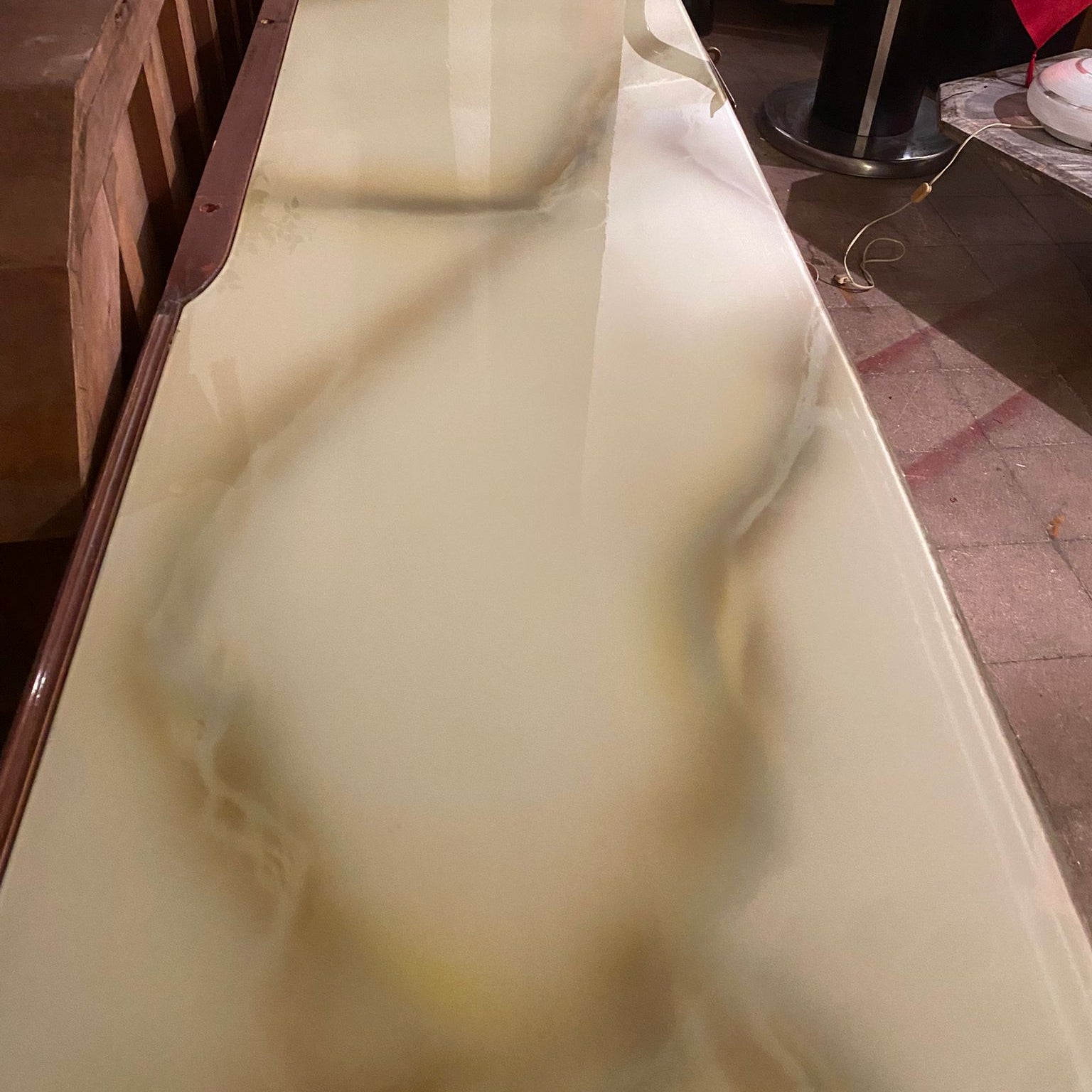Long, narrow marble-like table with a glossy surface in an indoor setting.