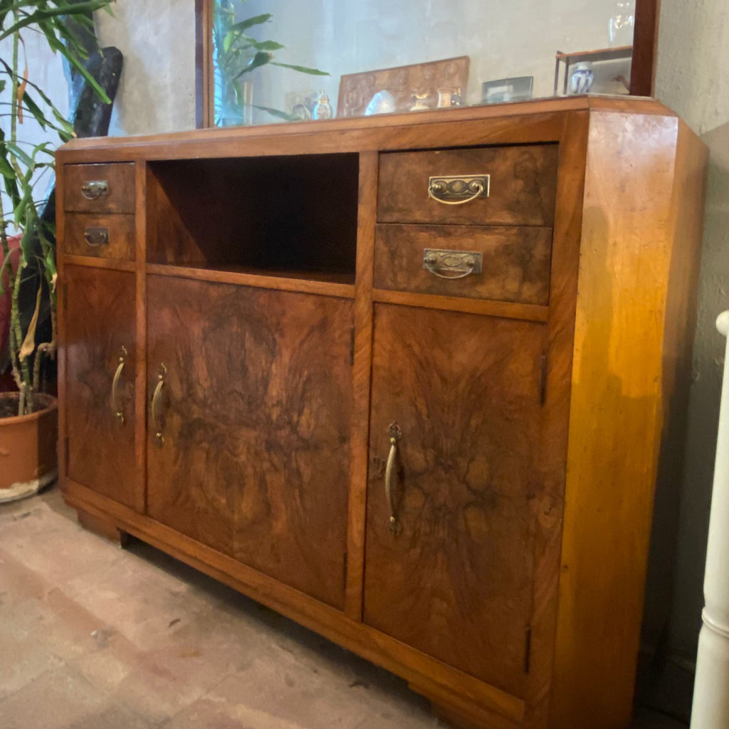 Wooden sideboard with drawers and doors in a room with plants and a window.