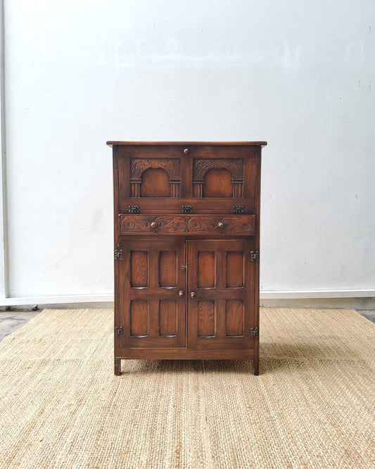 A Jacobean style carved oak Cocktail Drink cabinet with fall front over drawer and double cupboard
