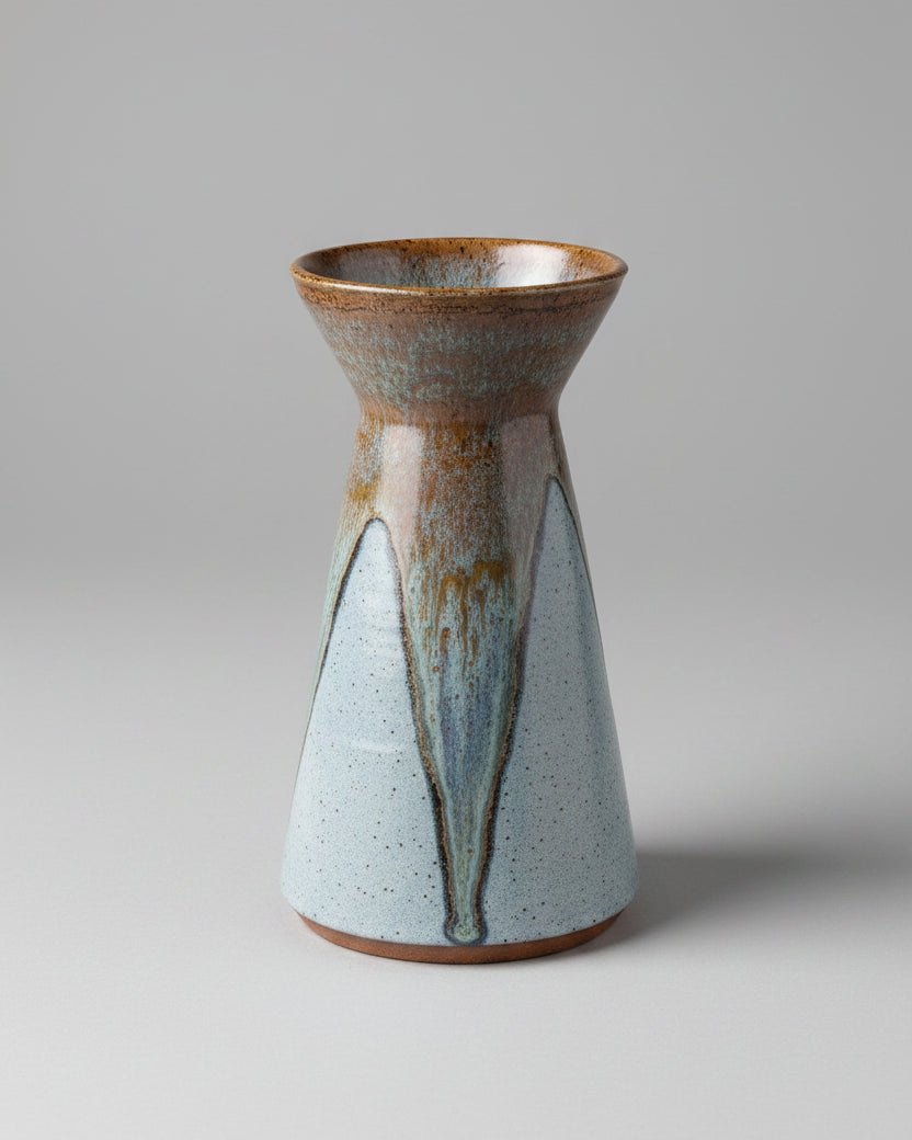 A handmade ceramic vase with a speckled and variegated pattern in shades of gray, brown, and white.
