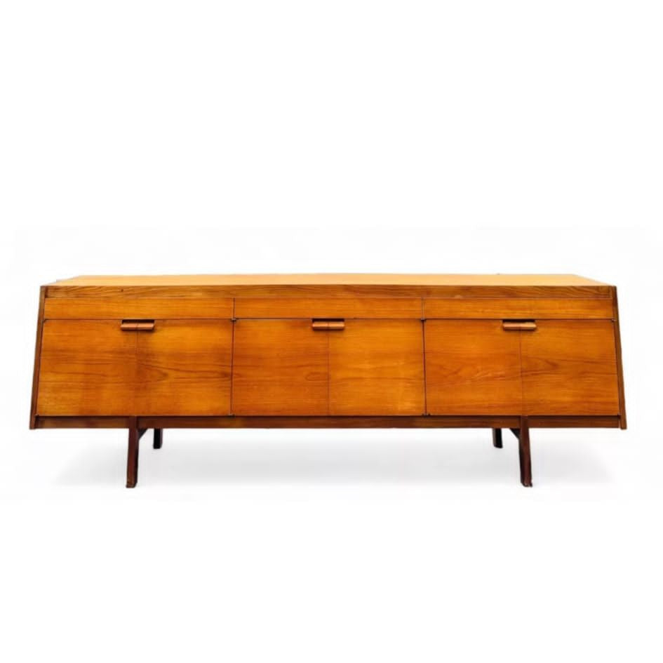 A mid-century modern teak wood sideboard with a tapered design and multiple drawers, displayed in a dimly lit room.