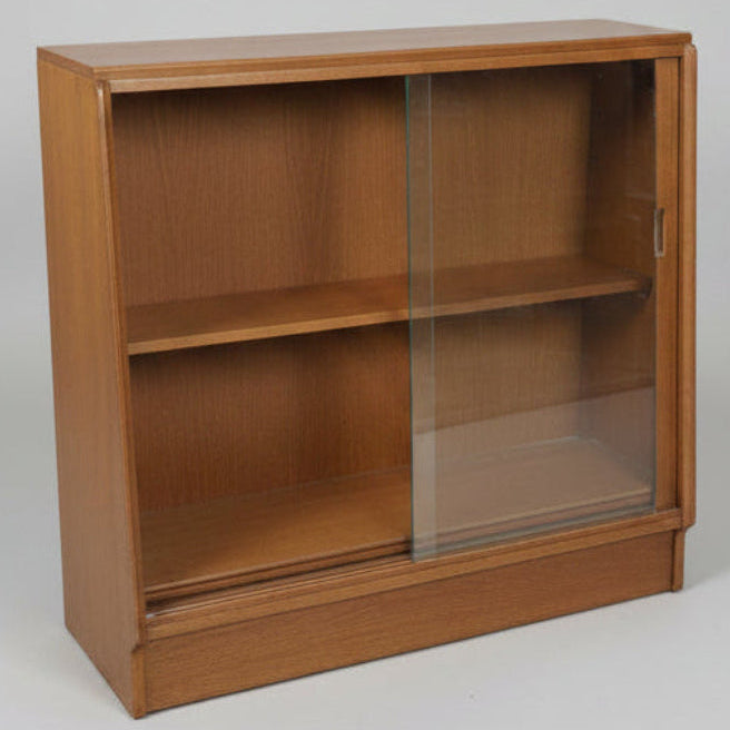 A vintage wooden display case with two glass doors and a base shelf, photographed in what appears to be a furniture store or warehouse.